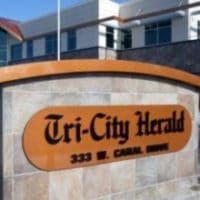 A stone sign for the Tri-City Herald at 333 W. Canal Drive stands before a modern commercial building.